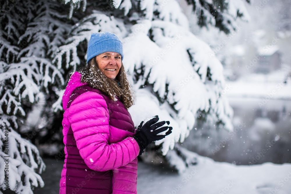 Fototapeta premium A happy middle aged woman holding a snow ball on a cold and snowy day in Colorado, USA