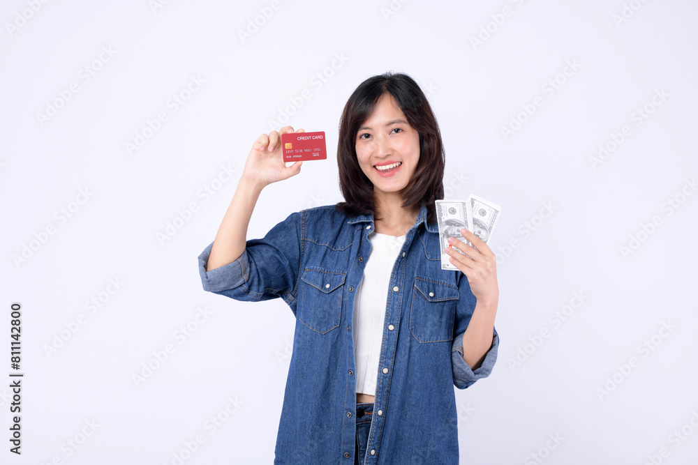 Asian woman wearing denim jean is holding dollar and credit card against a white background, financial payment concept. Asian woman wearing denim jean is holding dollar and credit card against a white background, financial payment concept.