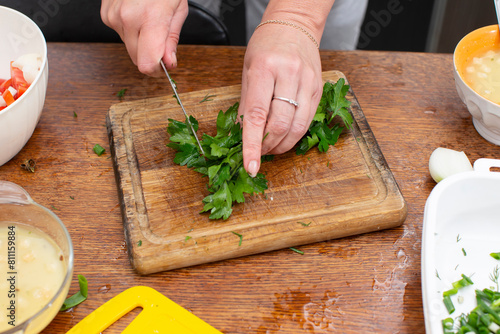 Hands chop green onions on a cutting board. Prepare vegetable salad.