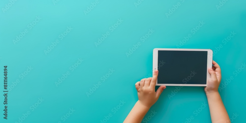 A child holding a tablet with a black screen. The tablet is on a blue background. The child is looking at the screen, possibly playing a game or watching a video A child holding a tablet with a black screen. The tablet is on a blue background. The child is looking at the screen, possibly playing a game or watching a video