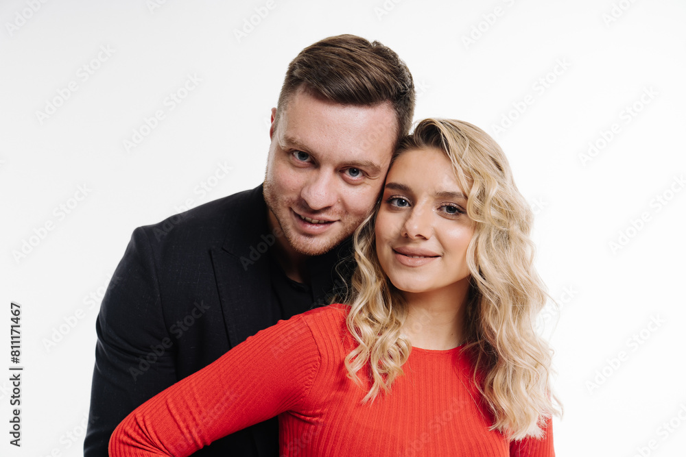 A man and woman are posing for a picture in red. The man is wearing a black suit and the woman is wearing a red shirt.