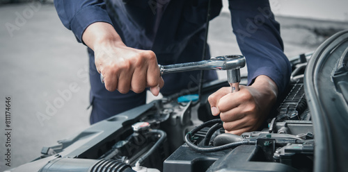 Mechanic using wrench while working on car engine outside the service center , Repair and service.