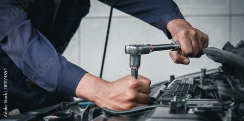 Mechanic using wrench while working on car engine outside the service center , Repair and service.