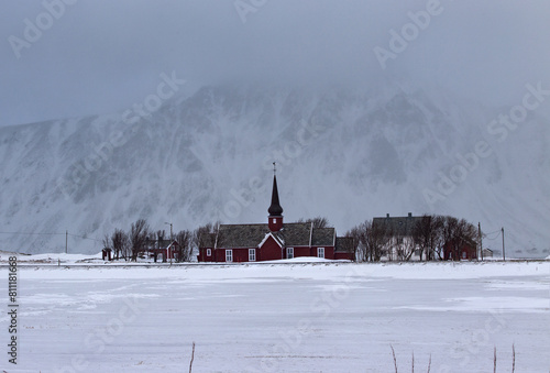 The parish church in Flakstad in foggy winter covered with snow, a red wooden chapel from 1870, near Ramberg Lofoten, Norway