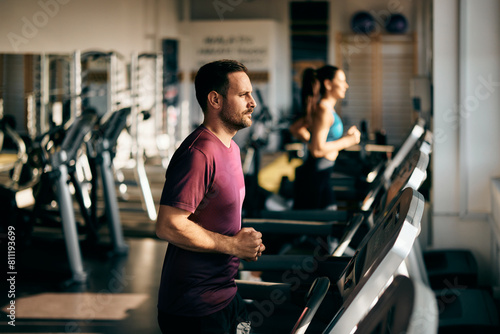 Focus on the tired male runner, running on a treadmill, at the gym.