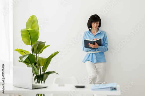 Professional adult caucasian female psychologist writing in paper notebook isolated on white wall background. Psychotherapy services, mental health professional concept. Copy space for advertising