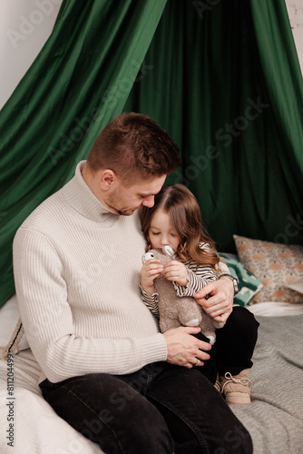 Happy Father's Day. Young daddy soft embraces his adorable little child daughter at home bedroom on bed. Tender single dad cares hugs small kid enjoy sweet moment together. Fatherhood. Children's day