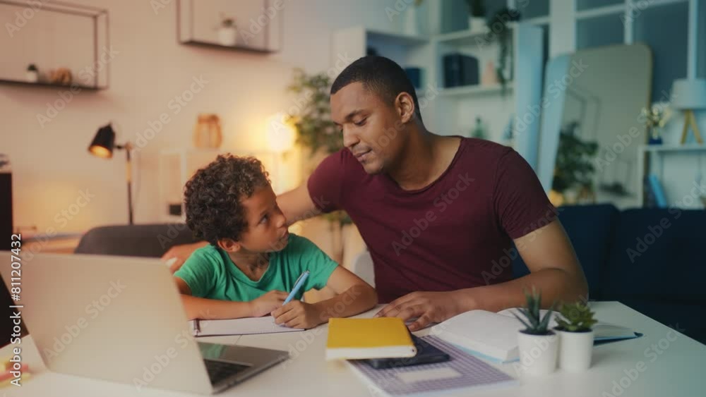 Caring father mentors son in homework, celebrates with high five, support Caring father mentors son in homework, celebrates with high five, support