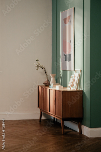 Elegant interior showcasing a mid-century modern wooden sideboard with artistic decor items, framed by a contrasting teal and grey wall.