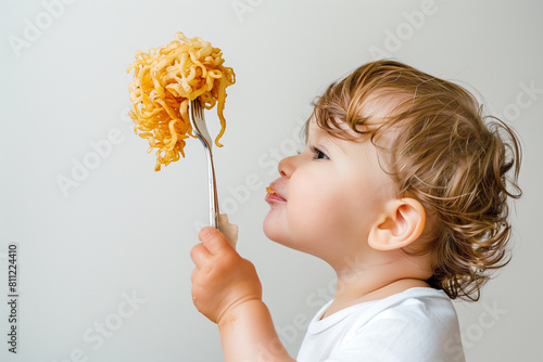 a privileged American toddler enjoys a gourmet experience of fried noodles, elegantly slurping them from a fork against a white backdrop, symbolizing the cultural richness and culi photo