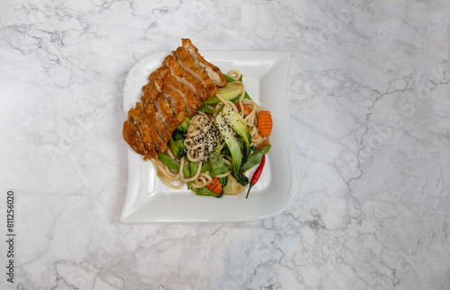 Fried crispy duck and udon noodles with vegetables, Asian cuisine.