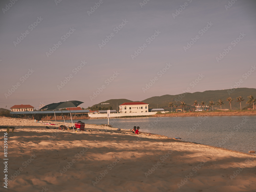 Sunny Beach Scene with People Relaxing on Sand and Colorful Kite Flying in Clear Blue Sky Sunny Beach Scene with People Relaxing on Sand and Colorful Kite Flying in Clear Blue Sky