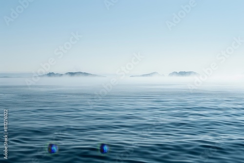 A body of water with a few small islands in the distance on a misty morning, A misty morning on the open ocean, with fog enveloping distant islands on the horizon