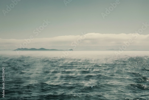 A vast body of water with a small island barely visible in the distance on a misty morning, A misty morning on the open ocean, with fog enveloping distant islands on the horizon