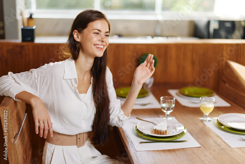 Romantic Dinner for Two A Beautiful Woman Enjoying a Homemade Meal at a Stylish Dining Table With a plate full of delicious food, a piece of cake, and a glass of wine, she is smiling ecstatically The photo