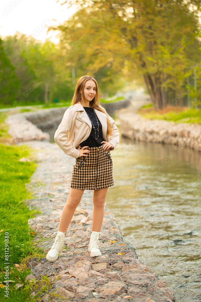 A young smiling girl walking in an autumn park in a good mood. Teenage girl, portrait against a background of nature. Fashion style trend. A young smiling girl walking in an autumn park in a good mood. Teenage girl, portrait against a background of nature. Fashion style trend.