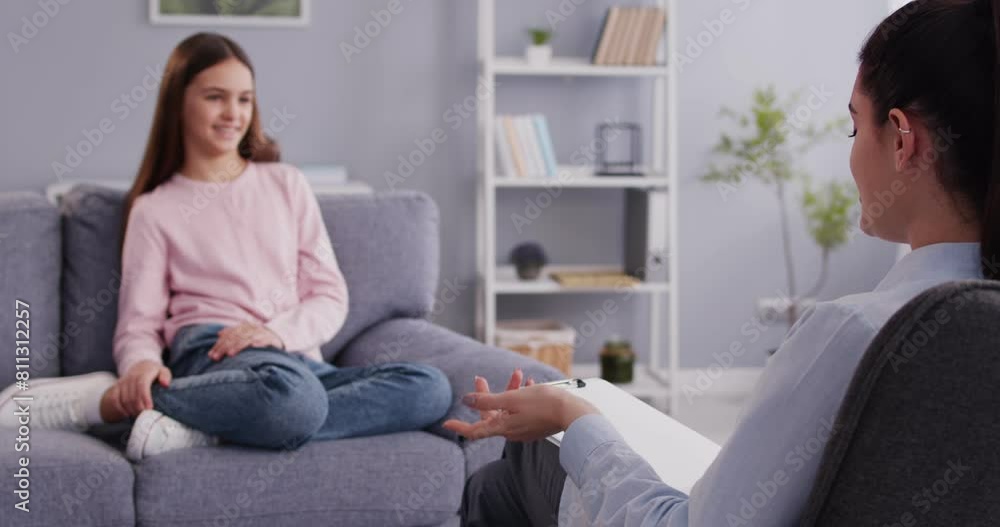 Portrait of a psychologist woman doctor making notes consulting teenage child girl smiling patient during therapy session at office. Psychotherapy and kids mental health concept. 4k video. Portrait of a psychologist woman doctor making notes consulting teenage child girl smiling patient during therapy session at office. Psychotherapy and kids mental health concept. 4k video.