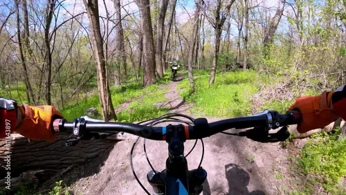 Two cyclists are riding on a difficult forest trail on mountain bikes. MTB. FPV.