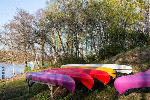 Canoe club station concept: set of colorful canoes lay near lake shore