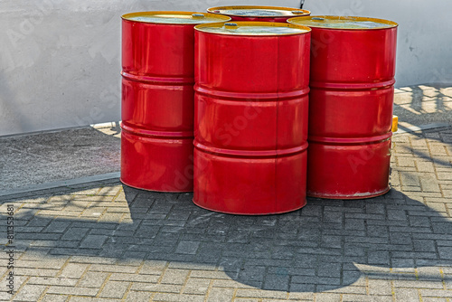 four red metal oil barrels stand outside on the harbor quay