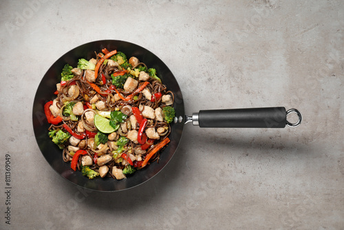 Stir-fry. Tasty noodles with meat and vegetables in wok on grey textured table, top view