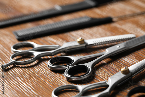 Hairdresser tools. Different scissors and combs on wooden table, closeup