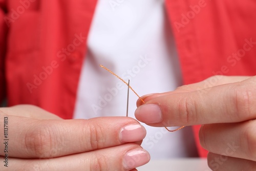 Woman inserting thread through eye of needle  closeup