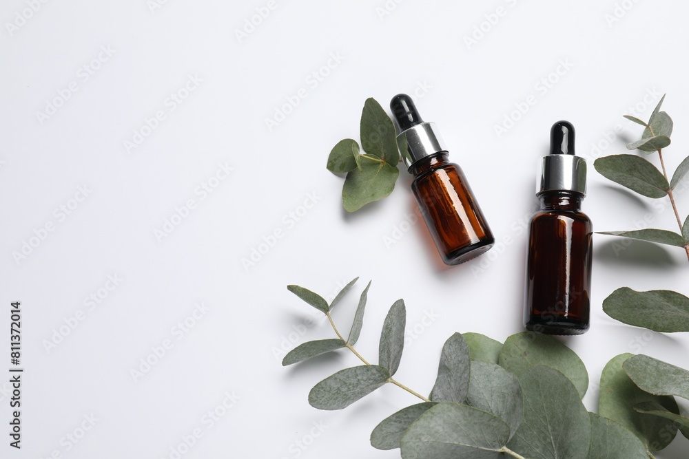 Aromatherapy. Bottles of essential oil and eucalyptus branches on white background, flat lay. Space for text Aromatherapy. Bottles of essential oil and eucalyptus branches on white background, flat lay. Space for text