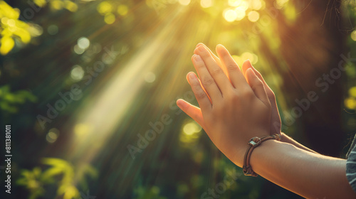 A heartwarming close-up of hands clasped together in unity during a family prayer or moment of reflection, with rays of sunlight filtering through the trees. Dynamic and dramatic c