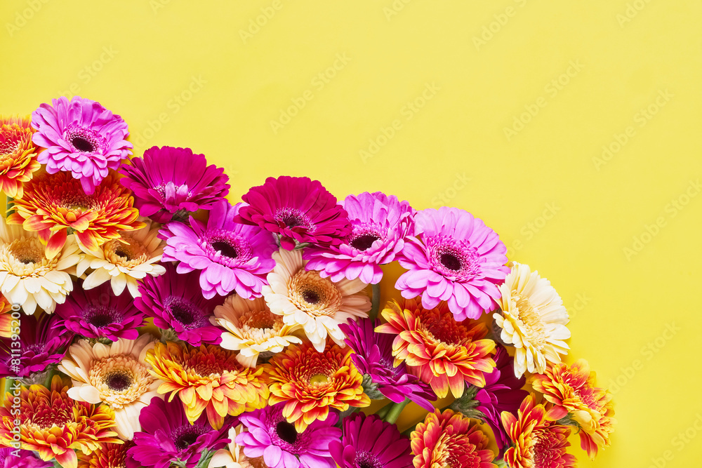 Obraz premium Bouquet of bright colorful gerberas on a bright yellow background. Copy space
