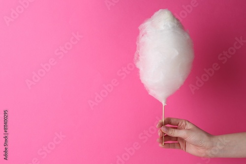 Woman holding sweet cotton candy on pink background, closeup. Space for text photo