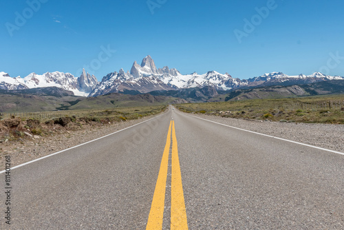 A long road with a yellow line down the middle and the Mount Fitz Roy at the background.