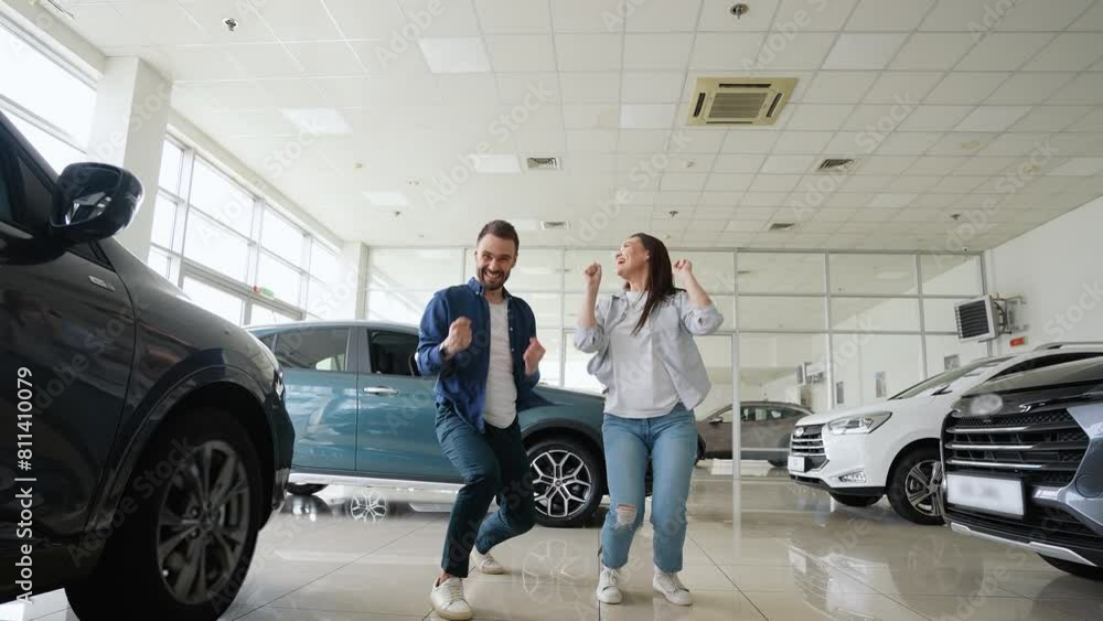 Happy couple jumping and dancing in a car dealership Happy couple jumping and dancing in a car dealership