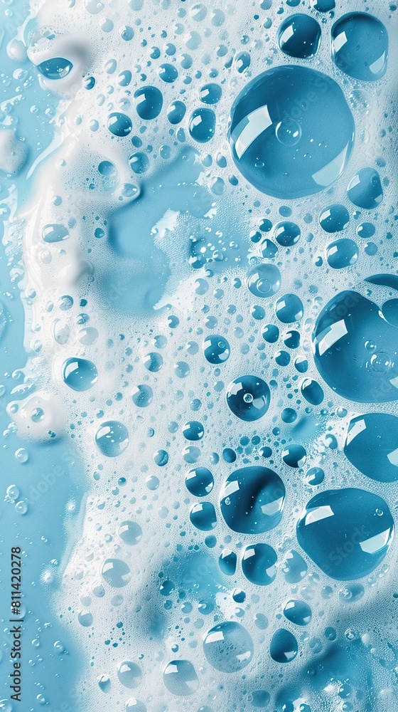 Soap foam with bubbles and water drops on a blue surface. Bright bubble soap foam in a touch of freshness and dynamism on a light blue background.