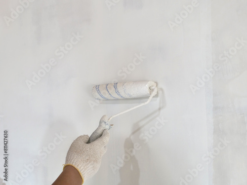 Painter hand holding roller brush painting new white wall, diy interior exterior home renovation