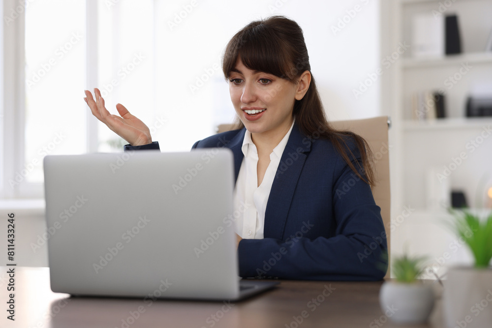Woman using video chat during webinar at wooden table in office Woman using video chat during webinar at wooden table in office