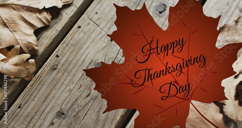 Image of happy thanksgiving day text over autumn leaf on wooden boards background