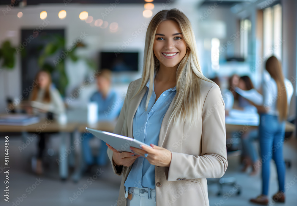 businesswoman smiling while holding a tablet in an office with a team working at a table businesswoman smiling while holding a tablet in an office with a team working at a table