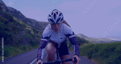 A Caucasian young adult is cycling up hill, focusing intensely