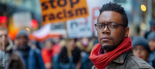 photo of a black man in front of a crowd, a meeting, which is chanting stop racism in order to protect human rights