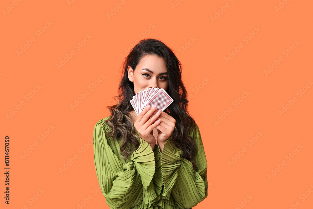 Beautiful young African-American woman with playing cards on orange background Beautiful young African-American woman with playing cards on orange background
