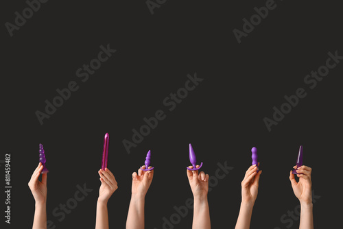 Female hands with different sex toys on dark background
