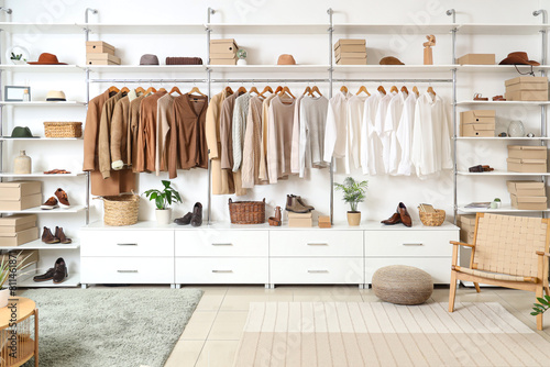 Interior of modern dressing room with wardrobe boxes, stylish clothes and accessories photo