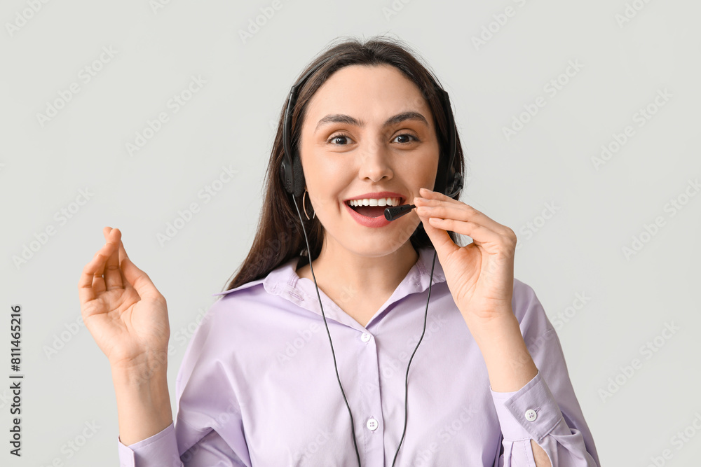 Happy female technical support agent in headset on grey background Happy female technical support agent in headset on grey background