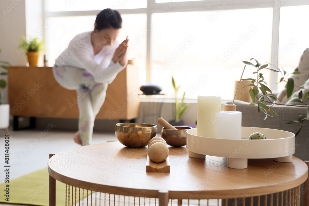 Candles with massage balls and Tibetan bowl on table of sporty woman doing yoga at home, closeup Candles with massage balls and Tibetan bowl on table of sporty woman doing yoga at home, closeup