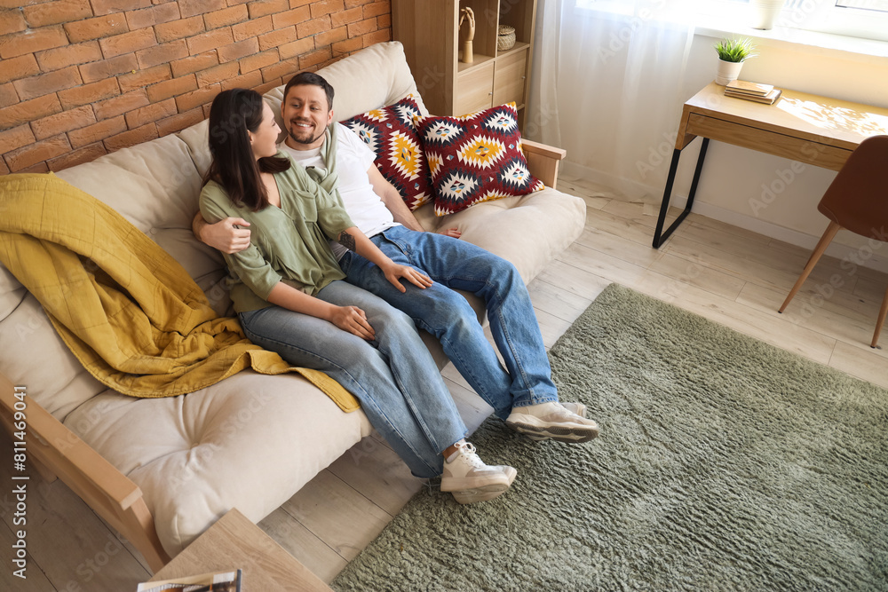 Obraz premium Young couple hugging on sofa with green carpet at home