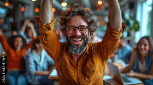 Bearded man in glasses rejoices raising hands in the office. photo