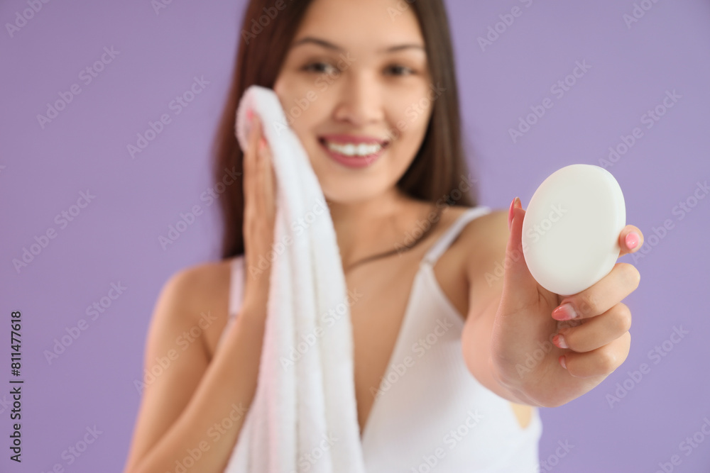 Young Asian woman with soap and towel on lilac background Young Asian woman with soap and towel on lilac background