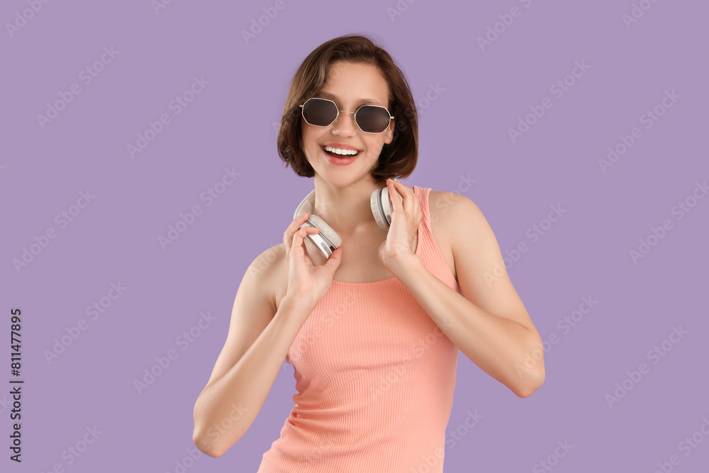 Pretty young woman with sunglasses and headphones on lilac background Pretty young woman with sunglasses and headphones on lilac background