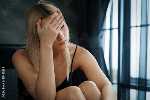 Young woman with critical depression and anxiety disorder from loneliness  mental sickness  or unwanted pregnancy  cuddling herself on dark bedroom. Overwhelming negative thought. Blithe